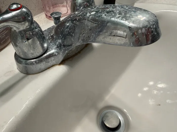 Bathroom faucet covered in hard water spots: before cleaning