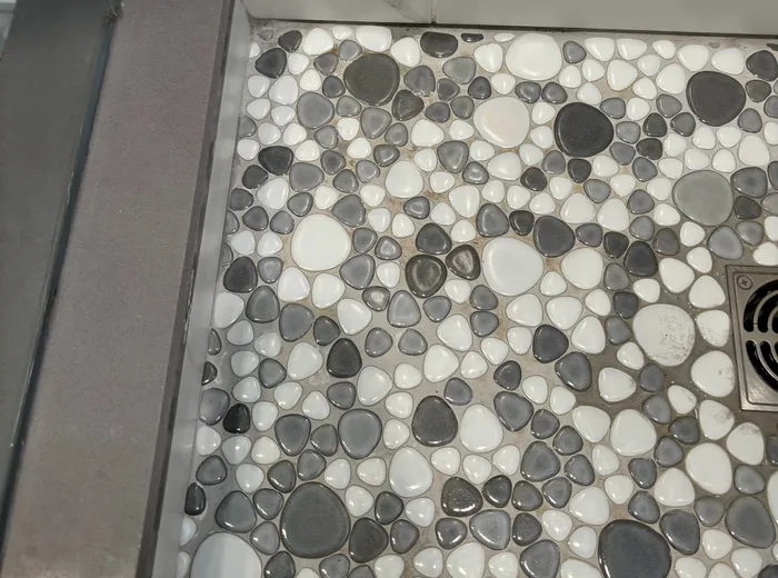Pebble shower floor with clean grout after Above and Beyond specialized cleaning